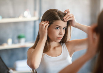 6 znakova da vam šampon ne odgovara: Odmah ga zamenite; zabrinuta devojka gleda svoju kosu