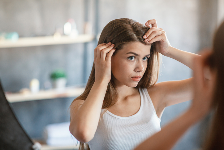 6 znakova da vam šampon ne odgovara: Odmah ga zamenite; zabrinuta devojka gleda svoju kosu