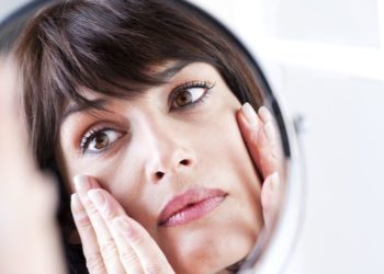 5 stvari koje odaju vaše godine i kako usporiti starenje kože; žena koja posmatra svoj odraz u ogledalu