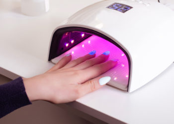 Da li je gel lak opasan; devojka drži ruku u UV lampi za učvršćivanje gel laka na noktima