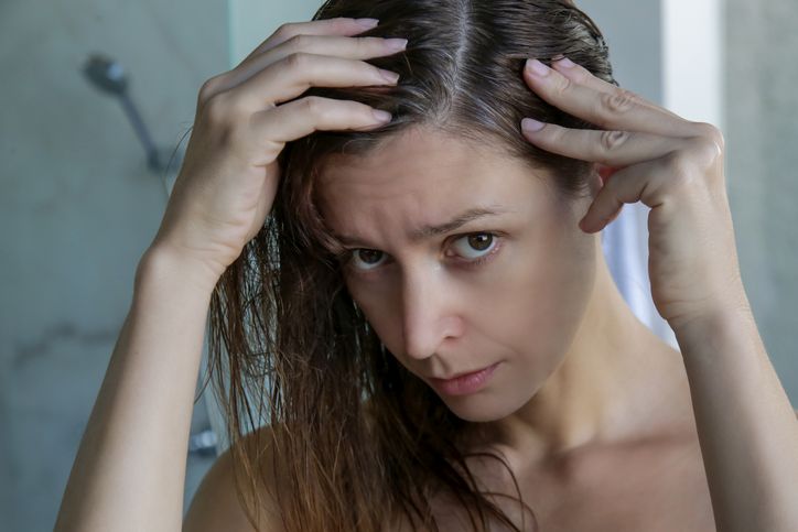Navike koje ubrzavaju pojavu sede kose; mlada devojka zabrinuto gleda sede vlasi u svojoj kosi
