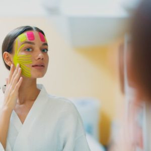 Face taping: Kako se koriste trake za zatezanje lica; žena sa zalepljenim trakama za zatezanje lica