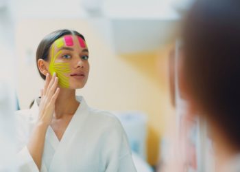 Face taping: Kako se koriste trake za zatezanje lica; žena sa zalepljenim trakama za zatezanje lica