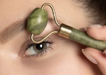 Kesice ispod očiju: Kako ih ublažiti; devojka masira područje oko očiju zelenim rolerom