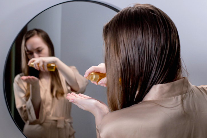 Ulje peperminta za bujnu i zdravu kosu; devojka stavlja ulje peperminta na kosu