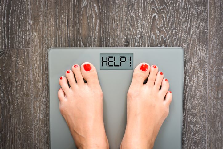 Kako odrediti svoju idealnu težinu; žena stoji na vagi za merenje