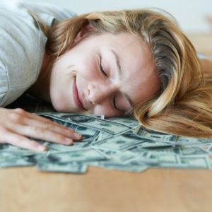 Kako da uštedite novac: Horoskopski znaci koji znaju kako se štedi; Zadovoljna žena koja leži na gomili para