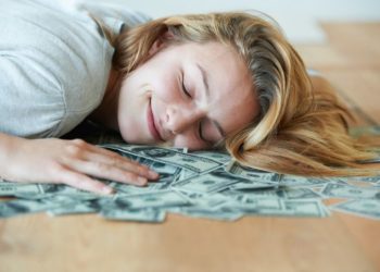 Kako da uštedite novac: Horoskopski znaci koji znaju kako se štedi; Zadovoljna žena koja leži na gomili para