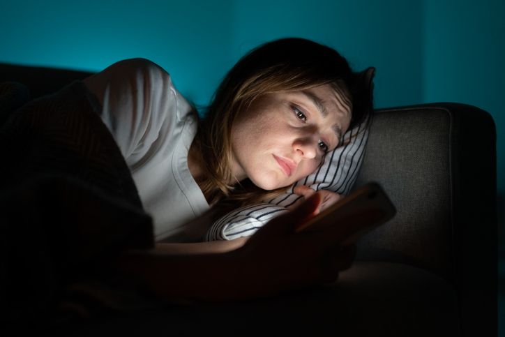 Zašto muškarci raskidaju bez objašnjenja; tužna žena leži u krevetu i gleda u telefon