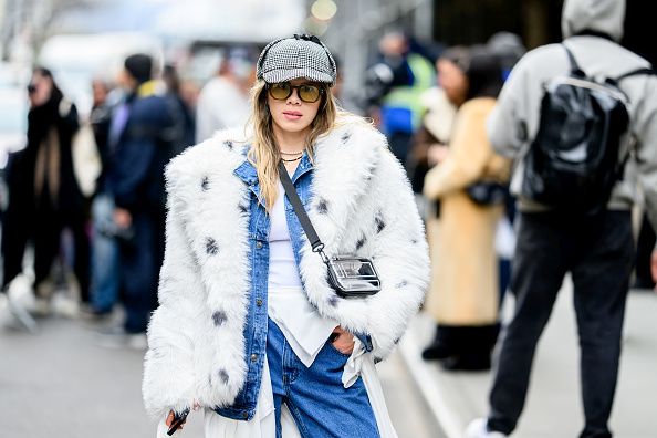 New York Fashion Week Street Style: 5 trendova koji vladaju; savršeno stilizovana devojka, u bundi i farmericama, sa kačketom naočarima, pozira na gradskoj ulici