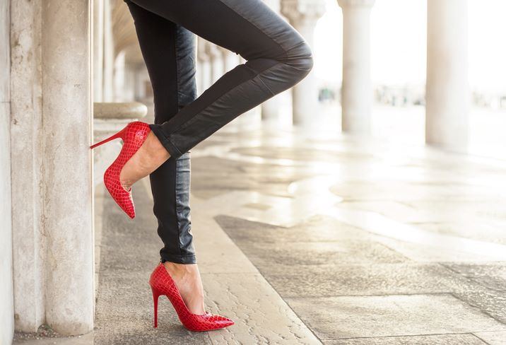 Kako nositi kožne pantalone: Najelegantnije kombinacije; Žena u crnim kožnim pantalonama i crvenim štiklama