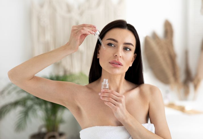 Kako koristiti serume za lice kao dermatolog; prelepa žena, duge crne kose, nanosi serum na lice