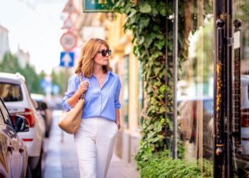Sa čim nositi bele pantalone ovog proleća; otmena dama šeta ulicom u belim pantalonama i plavoj košulji na pruge pantalonama