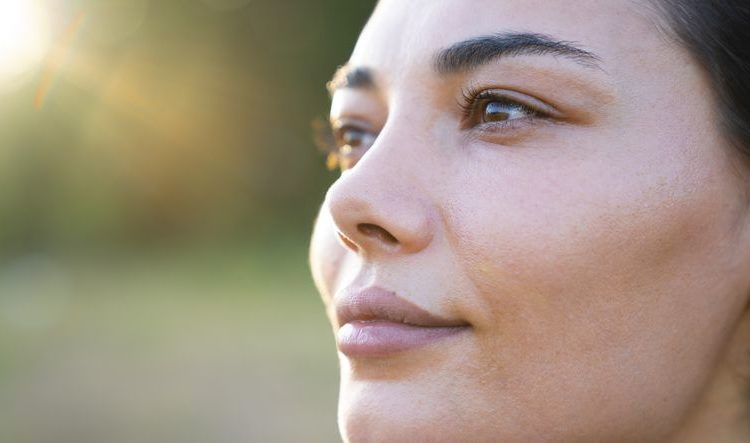 Suva ili dehidrirana koža: Ženski profil slikan u krupnom planu s blurovanom zelenom pozadinom