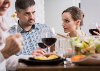 10 suptilnih znakova da vas njegovi roditelji ne vole; zabrinuti muškarac i žena sede za stolom, na ručku kod njegovih roditelja