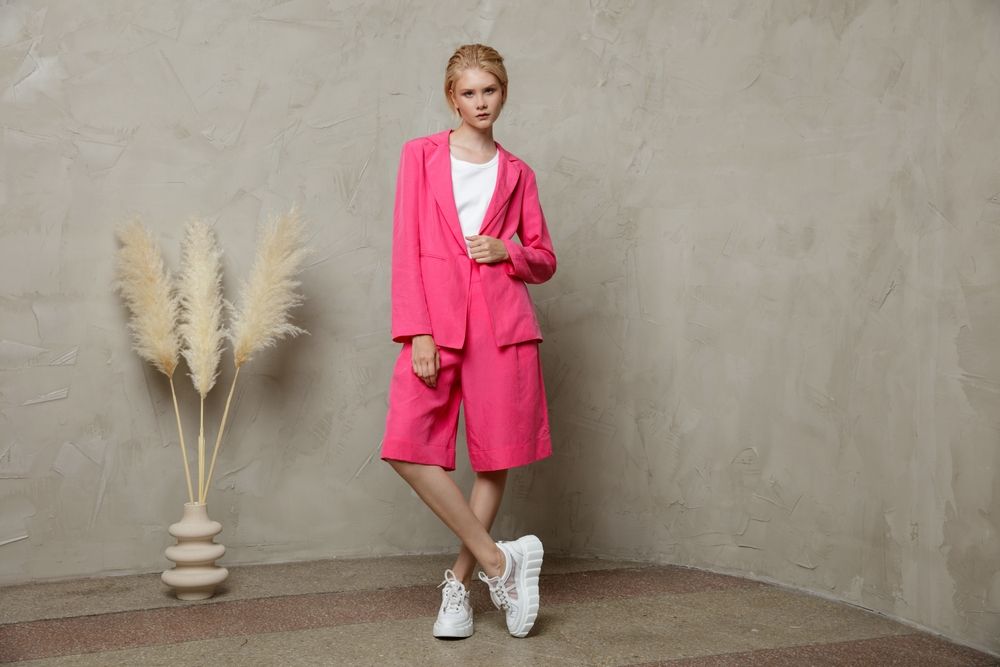 Kako nositi bermude ovog proleća; moderna devojka pozira u pink kompletu - bermudama i blejzeru ispod kojeg je obukla belu majcu